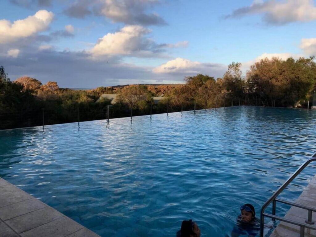 Infinity pool with views of trees and cloudy sky