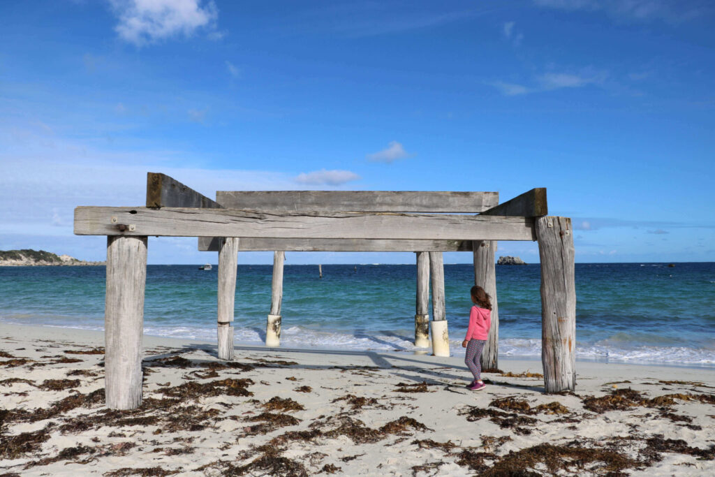 Girl walking and an old jetty at the beach