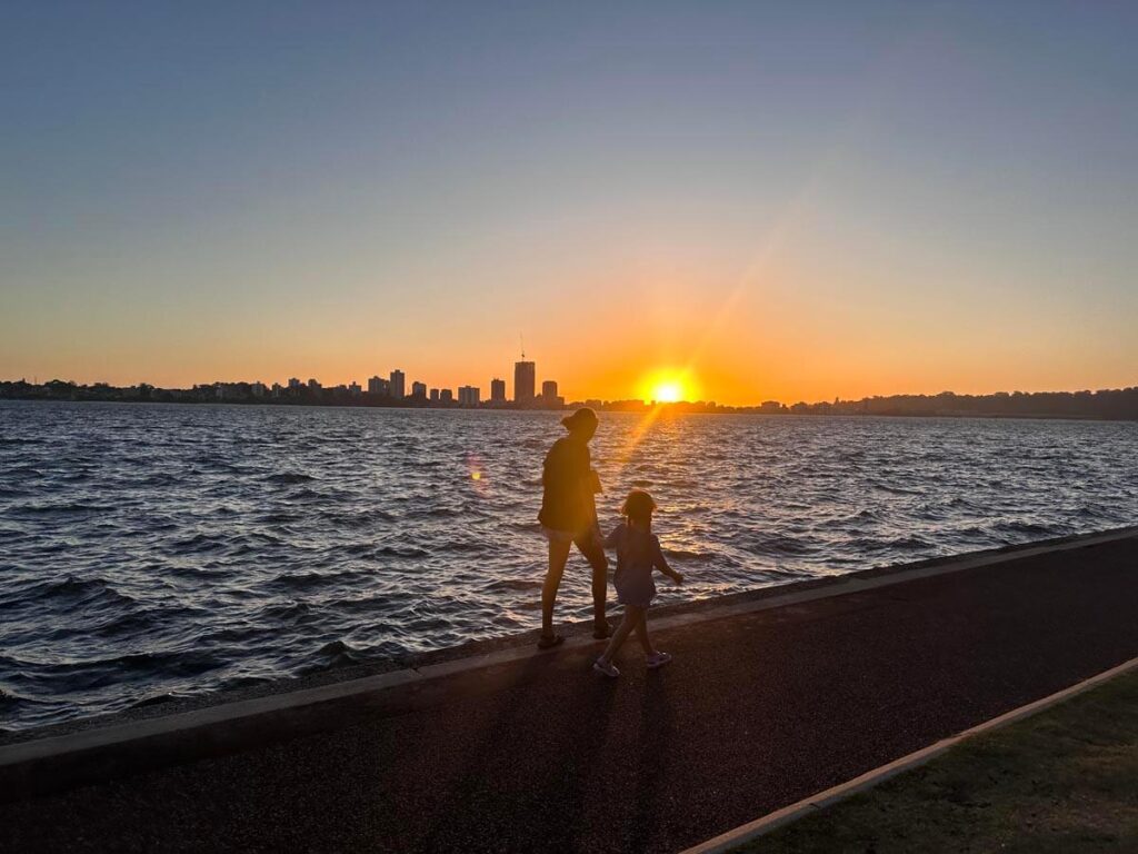 swan river sunset- two people walking at beach,